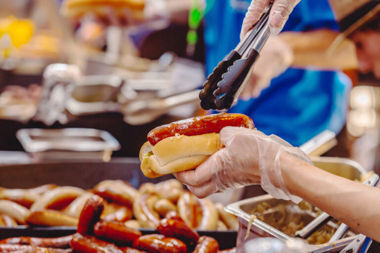 Closeup of staff holding Bratwurst sausage and bun in hand